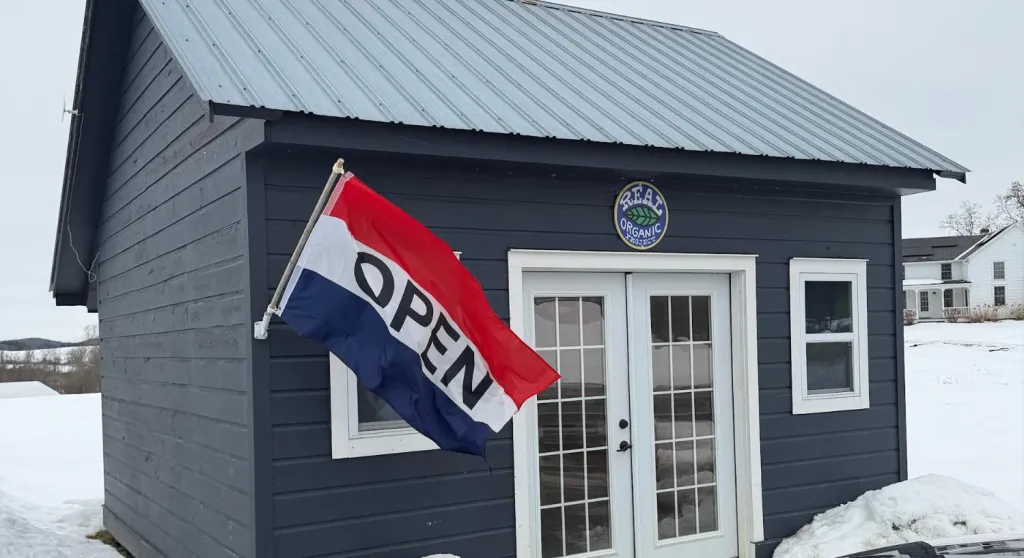 A small farm shop with an open flag in the snow