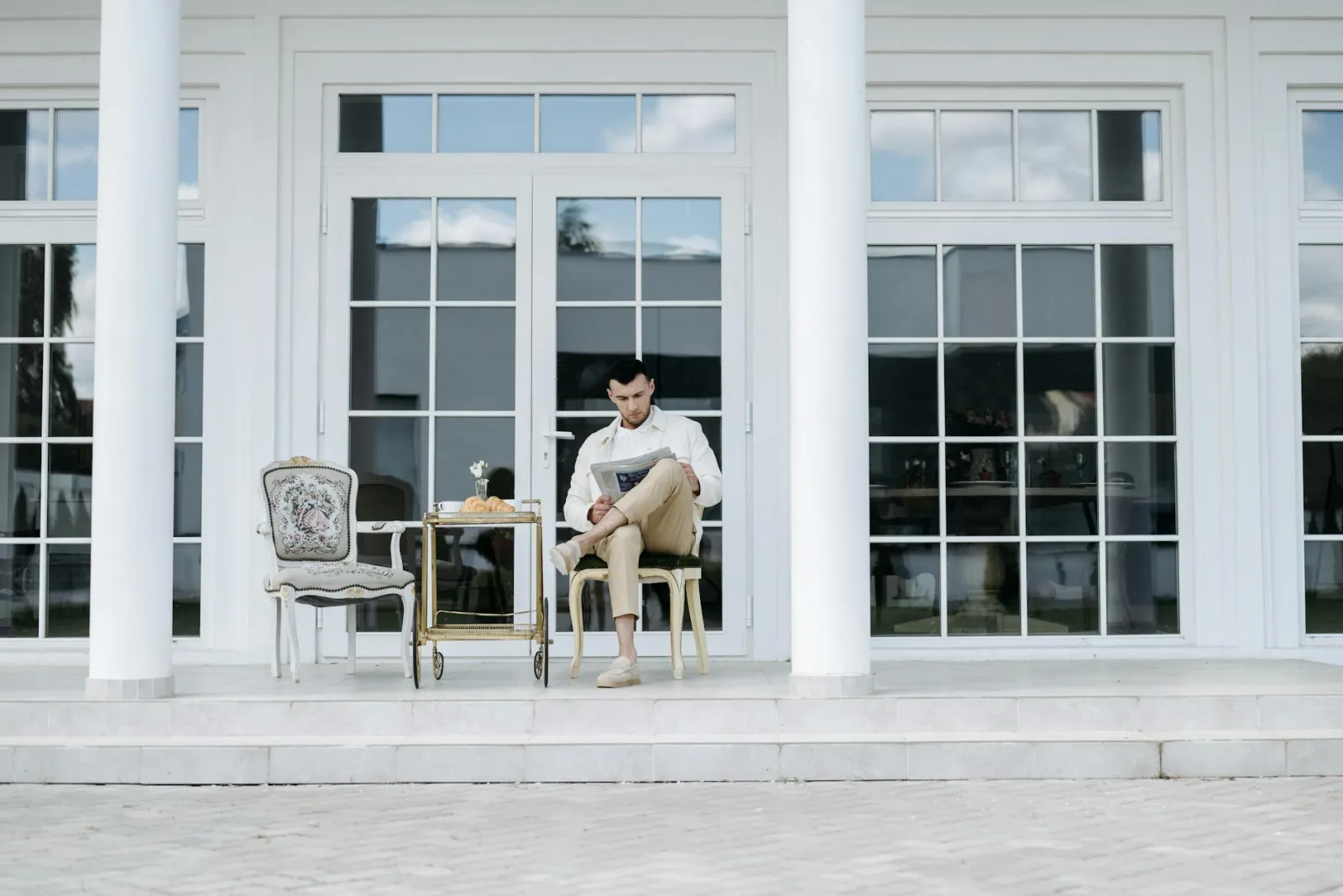 A person reading a newspaper on a front porch