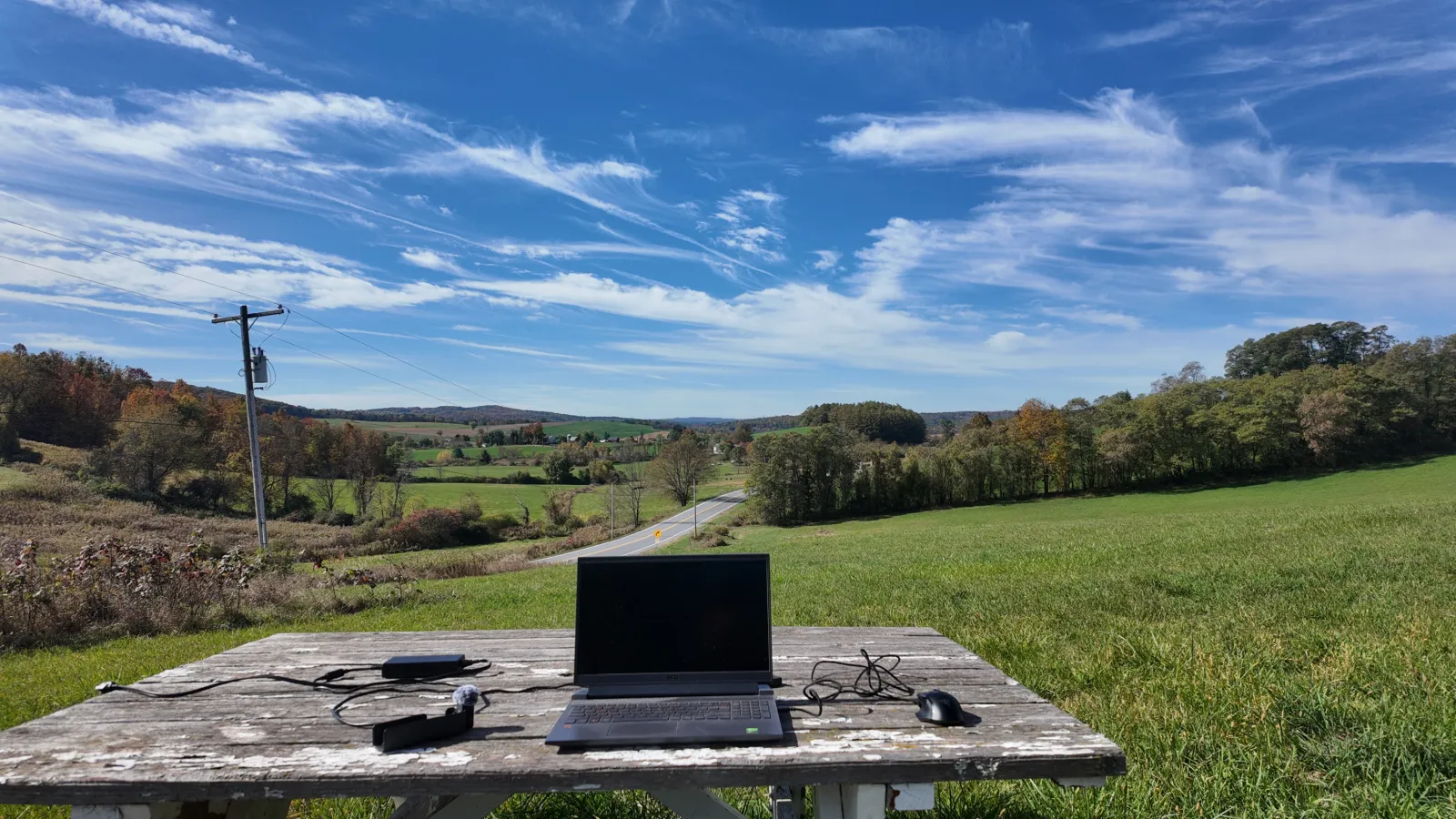A laptop set up for remote work beside a rural landscape